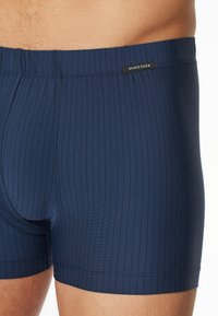 Boxer da uomo blu navy con texture a righe verticali, cintura elastica e un piccolo etichetta nera con la scritta "SCHIESSER."