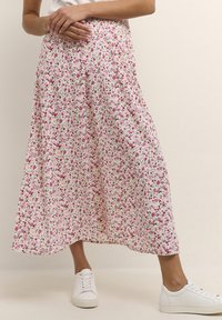 Floral midi skirt in white with pink and green patterns; elastic waistband; paired with white sneakers. Smooth, lightweight fabric.
