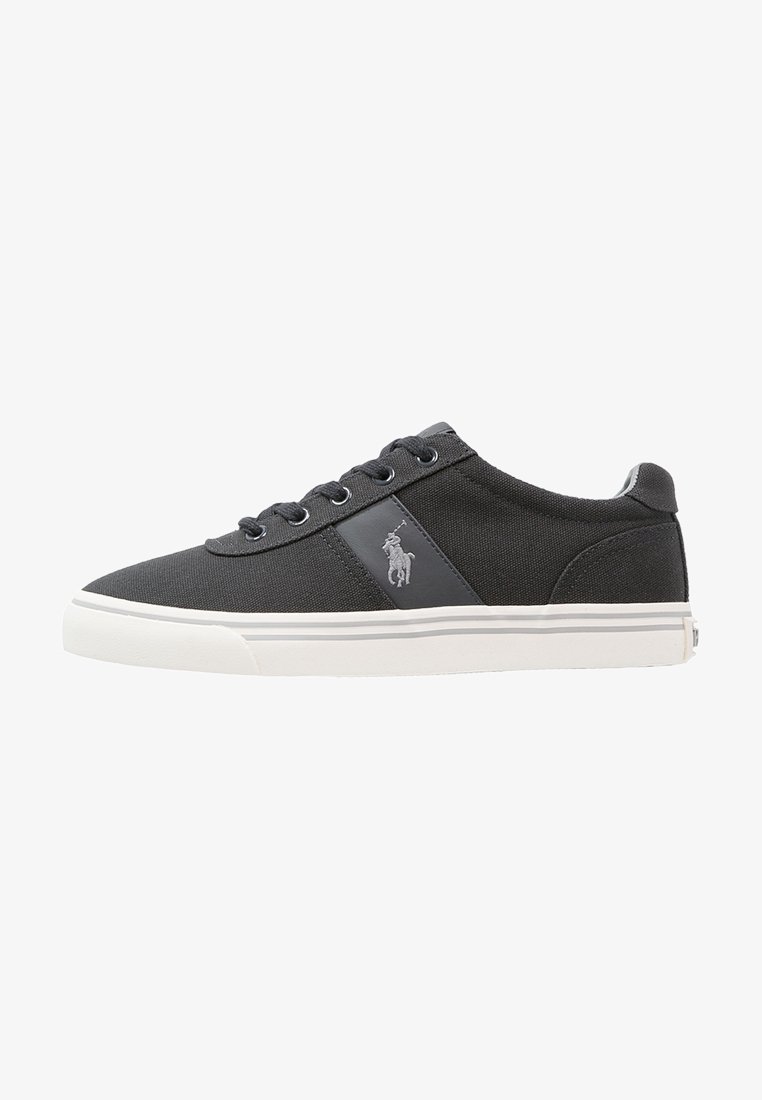 Sneakers in tela grigio scuro con suole in gomma bianca, dotati di un logo sul lato, lacci tondi e dettagli dalla texture liscia.