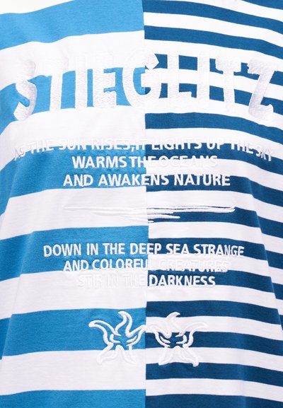 Ύφασμα με μπλε και λευκές ρίγες με κεντημένο λευκό κείμενο για την ανατολή, τον ωκεανό, τη φύση και τα βαθιά θαλάσσια πλάσματα, συν δύο κεντημένα αστερίες.