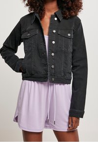 Černá džínová bunda s knoflíkovým zapínáním, náprsními kapsami a stříbrným kováním. Má zkrácený střih a pevnou texturu tkaniny.