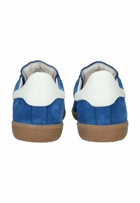 Mėlyni zomšiniai sportbačiai su baltais odiniais akcentais, turintys tekstūruotą rudą gumos padą. Kulnai yra apvalūs ir turi lygų dizainą.