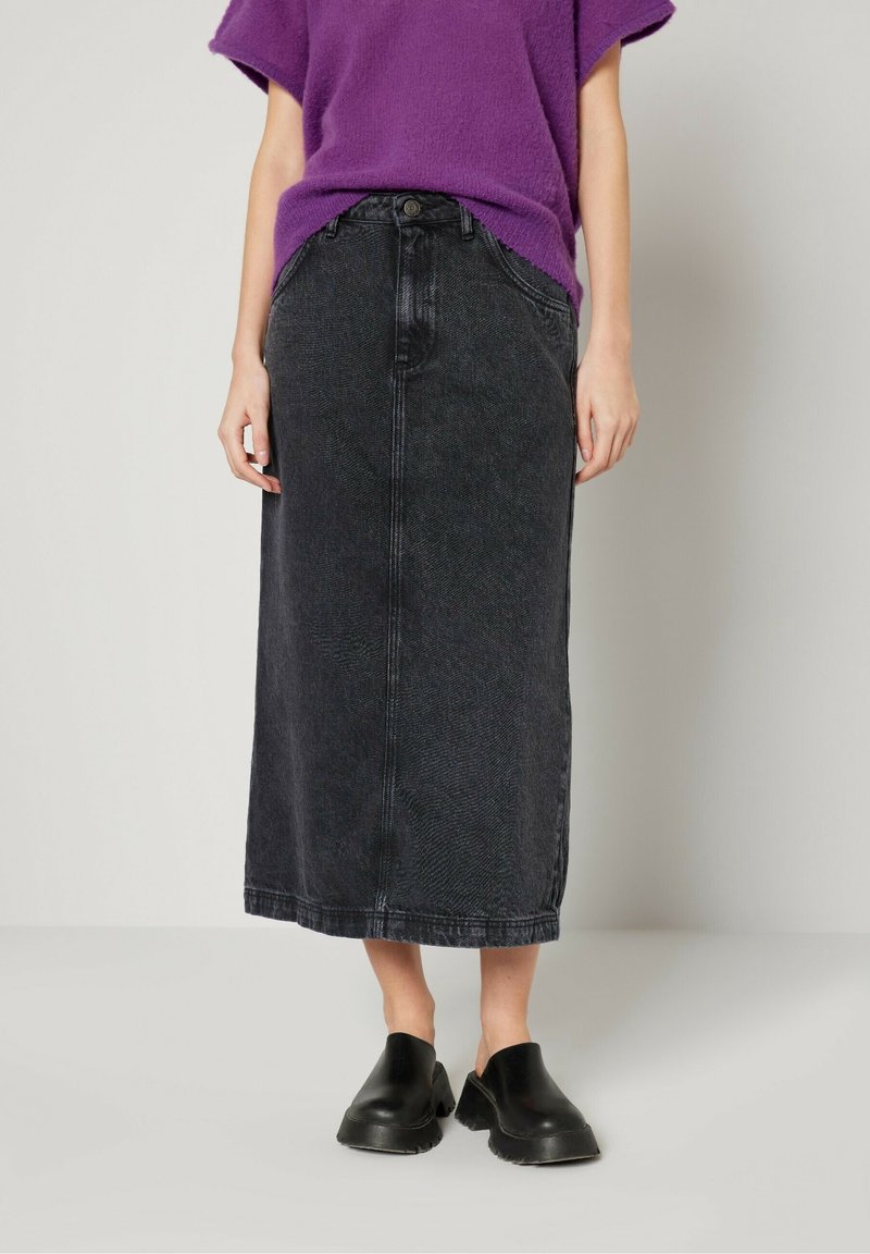 Svart denim midi kjol med rak skärning, har en framfick, bälteshällor och en knappstängning. Kombineras med svarta träskor.