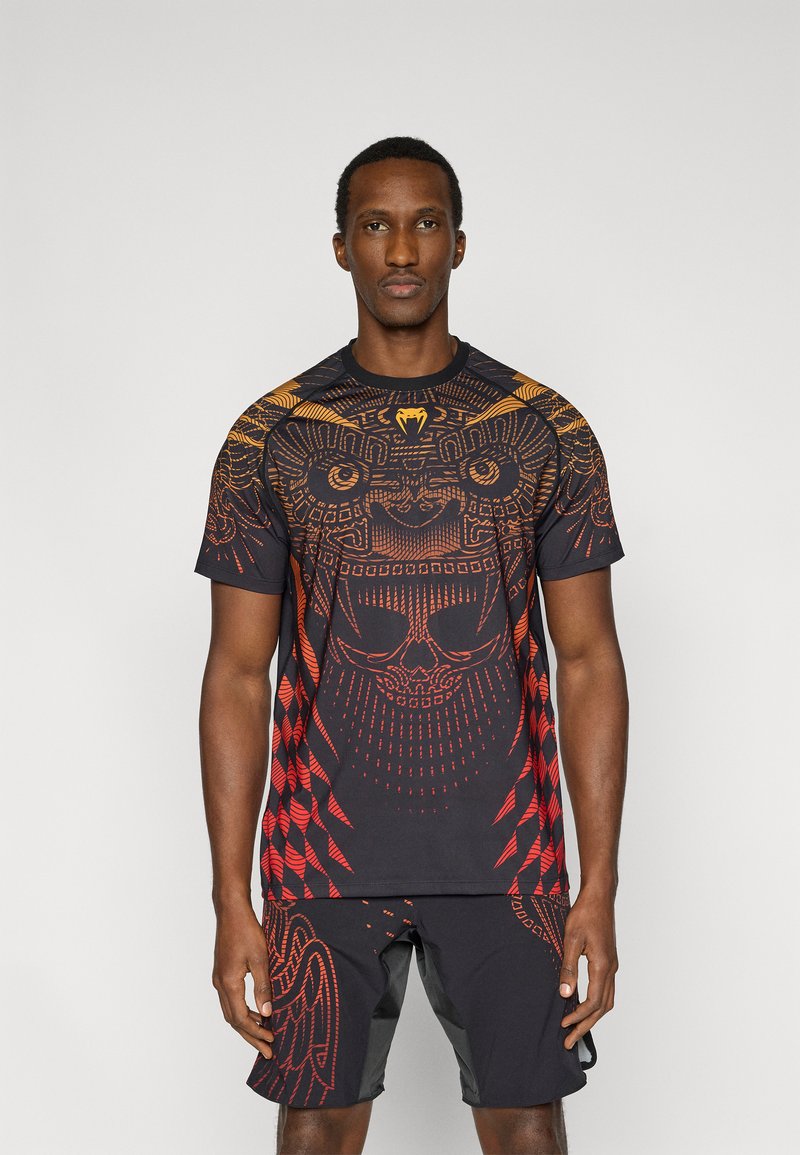 Μαύρο αθλητικό πουκάμισο με περίπλοκα κόκκινα και πορτοκαλί σχέδια, κοντά μανίκια και στρογγυλή λαιμόκοψη, συνδυασμένο με μαύρο σορτς.