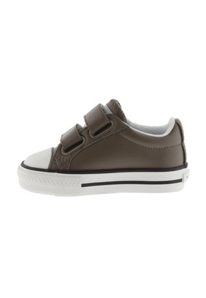 Zapatilla marrón para niño pequeño con punta blanca, dobles correas de velcro y suela blanca con línea negra, vista de lado.