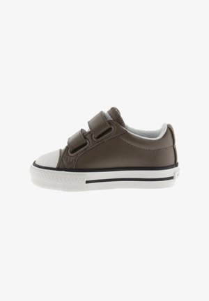 Zapatilla marrón para niño pequeño con punta blanca, dobles correas de velcro y suela blanca con línea negra, vista de lado.