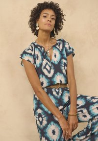 Top con motivo tie-dye blu e bianco, a maniche corte e scollatura rotonda. Il tessuto texturizzato mette in risalto il design vivace.