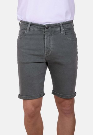 Pantalones cortos vaqueros grises con dobladillo vuelto, llevados por una persona con una camisa blanca metida, mostrados desde la cintura hasta la mitad del muslo.