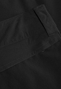 Svart tyg med en slät textur, med stickade sömmar och ett rektangulärt midjeband med en platt sektion för säker fastsättning.