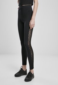 Sorte tights med gjennomsiktige leopardmønstrede sidepaneler, høy midje og tettsittende fasong. Kombinert med sorte snørestøvler.
