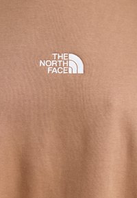 Hnědá mikina s výšivkou bílého loga The North Face. Měkká textura, ležérní design a střih s kulatým výstřihem.