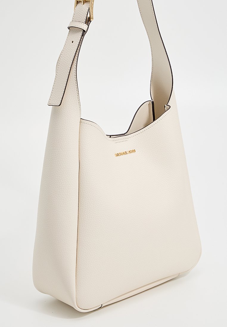 Borsa a spalla in pelle texturizzata bianco sporco con tracolla regolabile e logo dorato "Michael Kors" sul davanti.