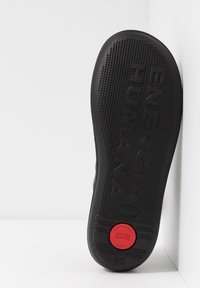 Black rubber shoe sole with textured surface, featuring "ENERGIA HUMANA" embossed, a red circular accent, and size "42" labeled.