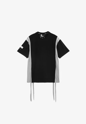 Camiseta negra de manga corta con paneles laterales grises y largas tiras de tela gris colgando del dobladillo.