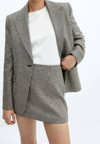 Ensemble blazer et jupe mini à motif pied-de-poule noir et blanc, présentant un ajustement tailleur, des revers crantés et deux poches avant.