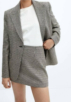 Ensemble blazer et jupe mini à motif pied-de-poule noir et blanc, présentant un ajustement tailleur, des revers crantés et deux poches avant.