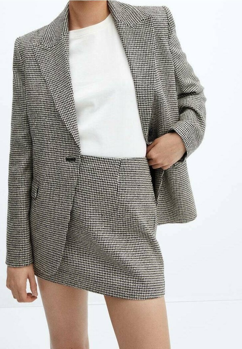 Ensemble blazer et jupe mini à motif pied-de-poule noir et blanc, présentant un ajustement tailleur, des revers crantés et deux poches avant.