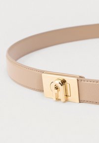 Bē�šs ādas josta ar gludu faktūru un kvadrātveida zelta metāla sprādzi, kas aprīkota ar unikālu aizslēga mehānismu.