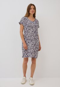 Lyhythihainen mekko tummansinisellä taustalla valkoisella leopardi-kuviolla. Valmistettu pehmeästä kankaasta, jossa on pyöreä kaula-aukko ja rento, suora malli.
