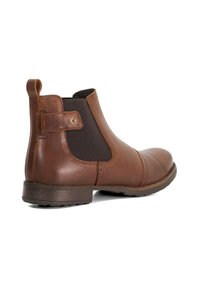Bottines Chelsea en cuir marron avec des panneaux élastiques sur les côtés, bout arrondi et un petit talon. Présente une languette à l'arrière pour un enfilage facile.