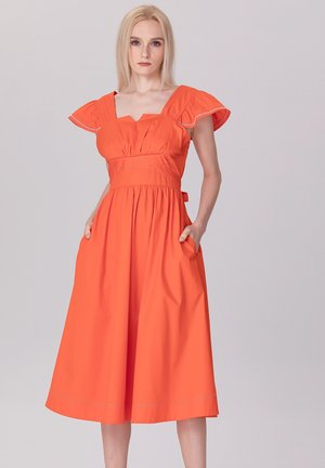 Robe en coton orange avec des manches courtes à volants, décolleté carré et taille cintrée. Dispose de poches latérales et d'une jupe longueur genou.