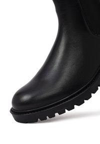 Stivale alla caviglia in pelle nera con una superficie liscia, punta arrotondata, pannelli laterali elasticizzati e una suola in gomma spessa con scanalature profonde.