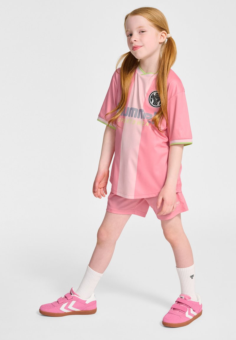 Rosa sporttröja med korta ärmar och kontrasterande ljusgröna detaljer, ihop med matchande shorts. Sneakers i rosa med vita detaljer.