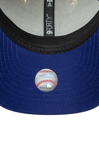 Tamna plava 9FORTY kapa s crnim vizirjem i okruglom naljepnicom MLB loga s grafikom bejzbol. Teksturovana tkanina.