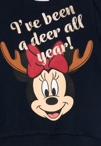 Tumepruun dressipluus, millel on suur trükitud multifilmitegelase nägu, millel on hairing, sarved ja sädelev tekst: "Ma olen olnud põder kogu aasta!"