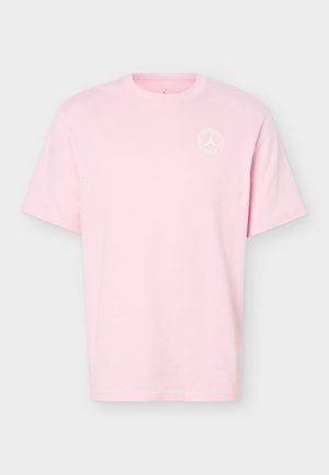 Lyserød T-shirt med korte ærmer og rund halsudskæring med en lille hvid cirkulær logo på øverste venstre bryst.
