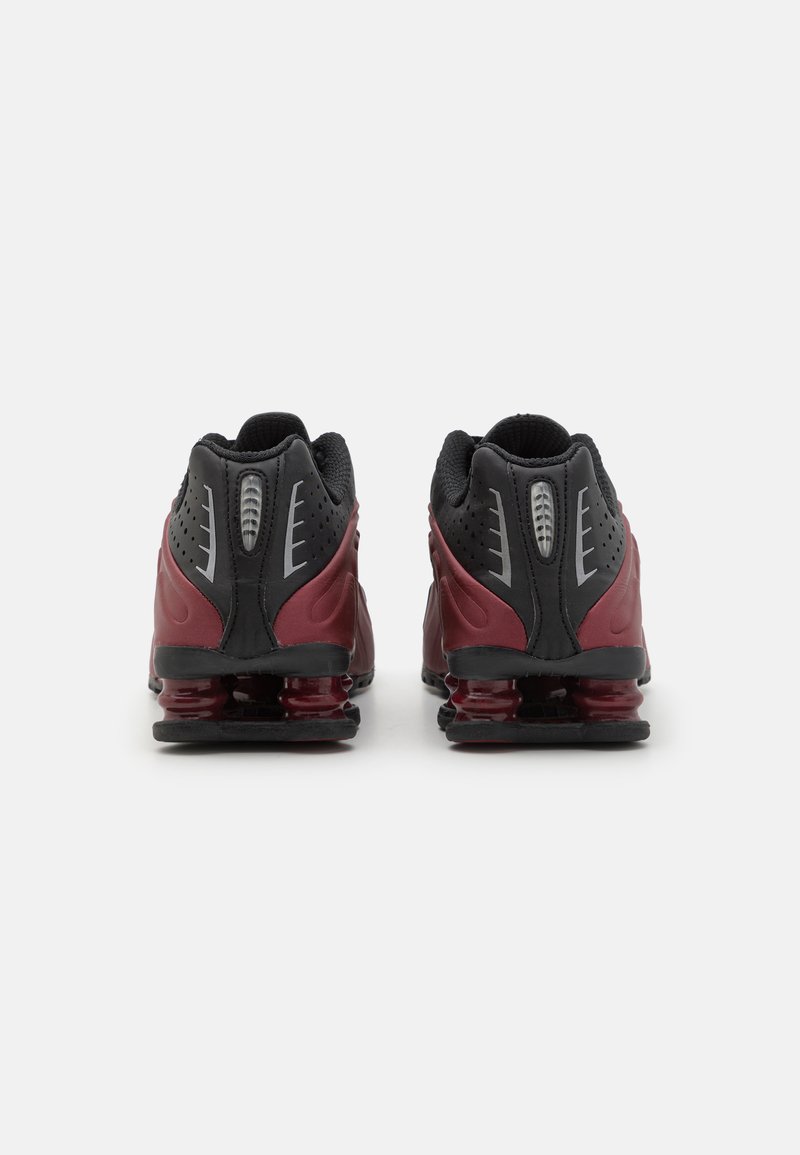 Baskets de sport noires et bordeaux avec un dessus en mesh et synthétique, présentant un amorti de talon prononcé et des détails perforés.