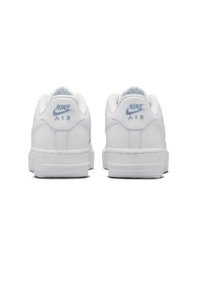 Valkoiset Nike Air -tennarit, joissa on sileä synteettinen päällinen, pehmustettu nilkkakuppi ja hienovaraiset siniset logovivahteet takana.