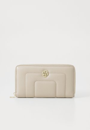 Beige pung med guldbeslag, der har et quiltet design og en tekstureret finish. Lynlåslukning og fremtrædende logo detaljer foran.