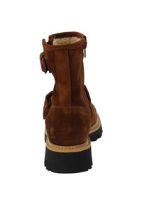 Stivale alla caviglia in suede marrone con fodera in pelliccia sintetica, suola in gomma nera, chiusura con doppio zip laterale e dettaglio decorativo con fibbia laterale.