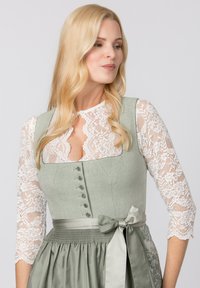 Traditionelles Kleid mit einem hellgrünen Oberteil, weißen Spitzenärmeln und einem gerafften Satinrock. Es verfügt über Knöpfe und einen passenden Ripsbandgürtel.