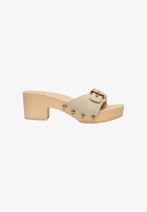 Zoccoli in suede beige con apertura sulla punta, tacco in legno, borchie dorate lungo il lato e cinturino regolabile con fibbia dorata sulla parte superiore.