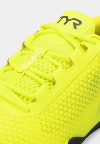Heldergele sneakers met een mesh bovenzijde, versterkte neuskap en contrasterende zwarte zool. Beschikt over getextureerde accenten en logo-details.