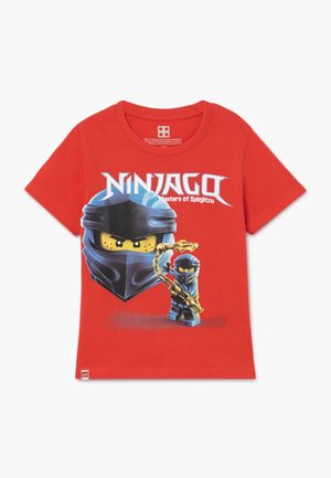 Camiseta roja para niños con el personaje LEGO Ninjago con máscara de ninja azul y arma dorada, texto "NINJAGO Maestros del Spinjitzu" arriba.