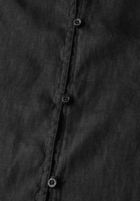 Tessuto in lino nero con chiusura a bottoni visibile, caratterizzato da una texture sottile e un dettaglio di cucitura pulito. Design minimalista, senza motivo.
