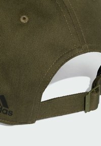 Olive green cap with a textured fabric, adjustable strap at the back, and a black logo on the side. Features a curved peak and ventilation holes.
