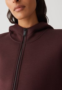 Bordeaux rode zip-up hoodie met hoge kraag en verborgen rits. Zachte stofstructuur en minimalistische ontwerpelementen.