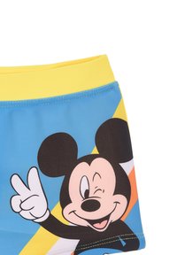 Bañador azul con una cinturilla amarilla. Presenta un gran diseño de un personaje de dibujos animados, patrones geométricos coloridos y costuras en contraste.