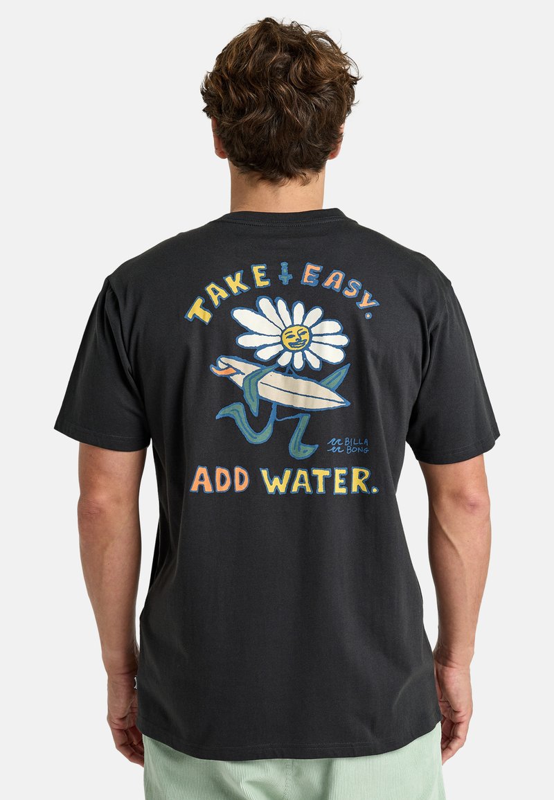 T-shirt en coton noir avec un graphisme coloré représentant une fleur souriante, une planche de surf et le texte "PRENDS LES CHOSES FACILE. AJOUTE DE L'EAU." au dos.