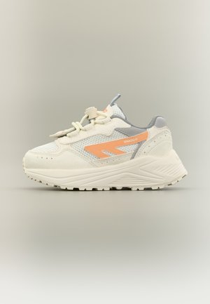 Fehér és szürke sportcipő narancssárga oldalsávval, amelyen "SHADOW" felirat olvasható, vastag talppal és csúszkás fűzőzárral, semleges háttér előtt.