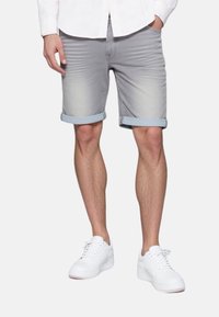 Harmaa farkkushortsit, joissa on vaaleansiniset cuffs, slim fit -muotoilu. Yhdistetty valkoisiin tennareihin rentoa ilmettä varten.