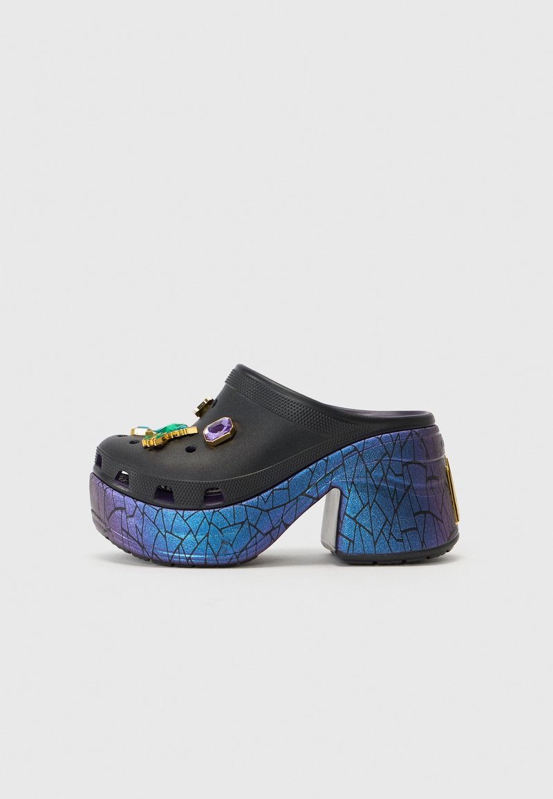 Sabot noir à enfiler avec un talon épais irisé bleu-violet et des breloques décoratives colorées en forme de pierres précieuses sur le dessus.