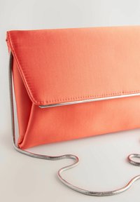Bolso de mano de satén coral con solapa triangular, ribete metálico y cadena de plata. Textura suave, diseño minimalista.
