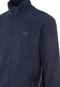 Mörkblå fleecejacka med hög krage, full dragkedja och en liten logotyp på bröstet. Har sidofickor och en mjuk textur.