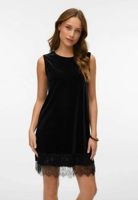Svart sammetsklänning utan ärmar med rundad halsringning och spetsdetaljer vid fållen. A-linjeformad, mjuk textur och eleganta detaljer.