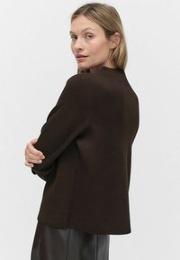 Pull en tricot marron avec un col rond, au fit décontracté et ourlet côtelé. Texture lisse, manches longues, détails de couture subtils.